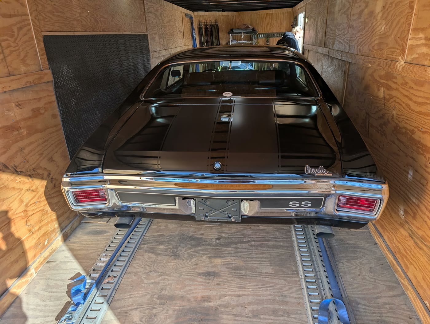 A classic strapped down to the floor rails inside the enclosed trailer